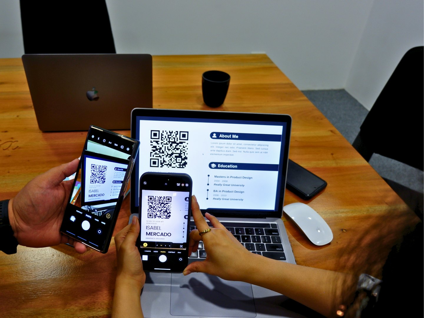 Dos personas escaneando códigos QR en sus teléfonos en un escritorio.